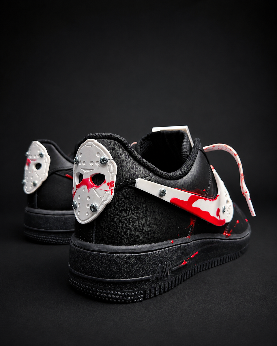 A pair of black low-top sneakers styled with hockey masks and red splatter details, photographed on a dark studio background.